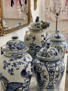 three blue and white vases sitting on top of a table next to a mirror