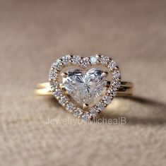 a heart shaped diamond ring with diamonds surrounding it