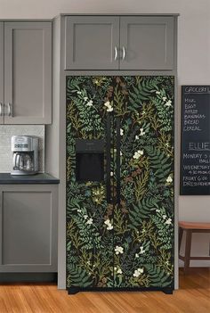 a kitchen with grey cabinets and a black floral wallpaper on the side of the refrigerator