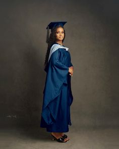 a woman in a graduation gown and cap poses for the camera with her hand on her hip