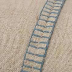 a close up view of the side of a pillow with blue stitching on it