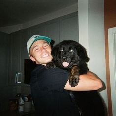 a man is holding a black dog in his arms while he smiles at the camera