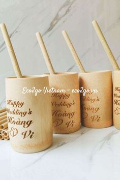 four bamboo drinking cups with engraved names and wooden spoons in the bottom one is empty