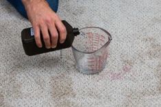 a man is using a measuring cup to measure the area in which he has spilled something