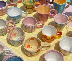 a table topped with lots of cups and saucers on top of a checkered table cloth