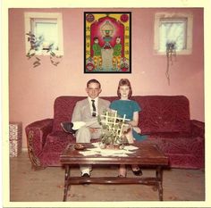 a man and woman sitting on a couch in front of a coffee table with flowers