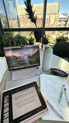 an open laptop computer sitting on top of a desk next to a notebook and pen