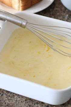 a white bowl filled with batter next to a loaf of bread