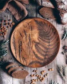 a wooden plate with some plants on it and nuts scattered around the plates, along with other items