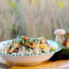 a white bowl filled with pasta and mushrooms on top of a table next to a plate of mushrooms