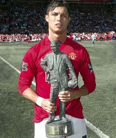 a man holding a trophy in front of a soccer field