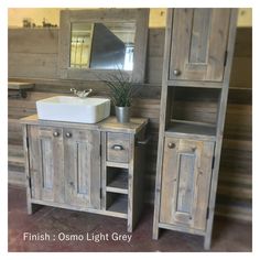 a bathroom with a sink, mirror and wooden cupboards in it's center