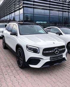 two white mercedes cars parked in front of a building