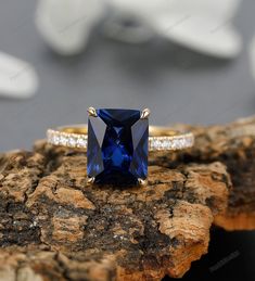 a ring with a blue stone and diamonds on it sitting on top of a piece of wood