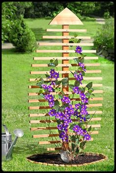 purple flowers are growing out of the ground in front of a wooden structure with an arrow on top