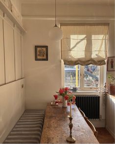 a wooden table sitting in front of a window next to a radiator with flowers on it