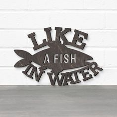 a metal sign that says like a fish in water on the side of a white brick wall