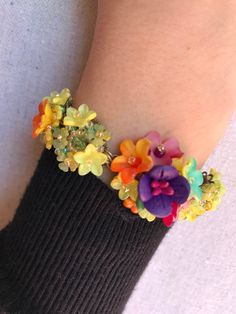 Pretty Petunia bracelet made with a stunning color mix of deep purple, yellow, orange and a pretty greeny turquoise. Made with an assortment of glass bead and handpainted resin flowers, it is meticulously sewn together by hand. This is just a really lovely piece and matches beautifully with our other pieces shown in Petunia. This is a quality piece of jewelry that will last a life time. Created by designer Colleen Toland who has been creating her unique style of vintage jewelry for more than 30 Handmade Rainbow Flower Jewelry, Whimsical Multicolor Flower Jewelry, Whimsical Multicolor Bracelets For Jewelry Making, Multicolor Flower-shaped Jewelry With Flower Decoration, Multicolor Resin Bead Jewelry, Whimsical Multicolor Bracelet Jewelry, Handmade Colorful Flower Bracelets, Handmade Colorful Flower Shaped Bracelets, Vibrant Yellow Beaded Bracelets As Gift