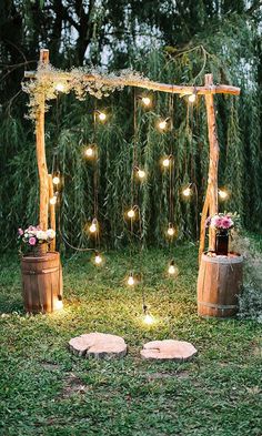 an outdoor ceremony with wooden barrels and string lights on the grass, surrounded by greenery