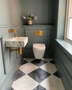 a white toilet sitting next to a sink in a bathroom under a window with flowers on the ledge