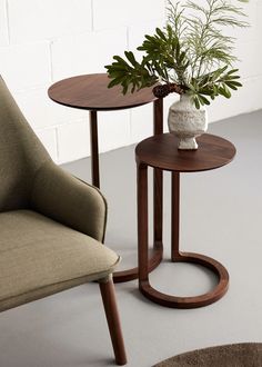 two small tables with plants in them sitting next to each other on the floor near a chair