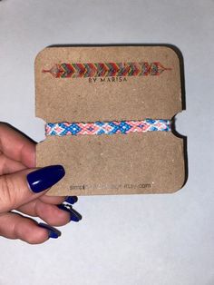 a woman's hand holding a small card with an arrow and braid on it