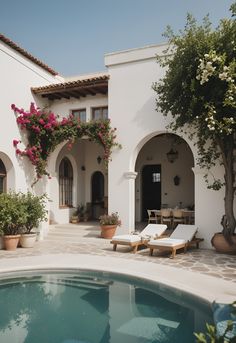 an outdoor swimming pool with lounge chairs and potted plants on the side of it