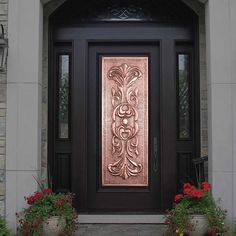 the front door is decorated with flowers and potted plants on either side, along with a decorative copper panel