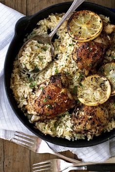 chicken and rice with lemons in a skillet on a white napkin next to a fork