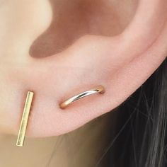 a close up of a person's ear with a gold bar in the middle