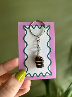 a hand holding a keychain with a glass bead hanging from it's side