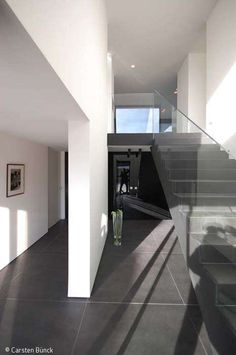 an empty room with stairs leading up to the second floor, and a vase in the foreground