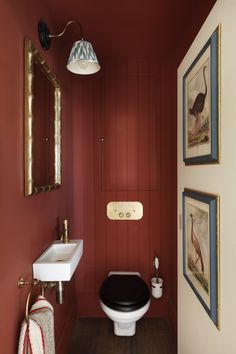 a bathroom with red walls and pictures on the wall