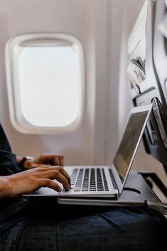 a person sitting on an airplane using a laptop