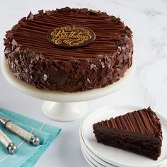 a chocolate cake sitting on top of a white plate next to a knife and fork