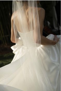 the back of a bride's wedding dress, with her veil blowing in the wind