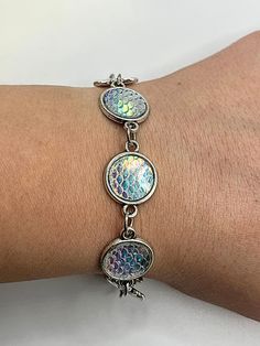 This beautiful, handcrafted bracelet features shimmering iridescent scales, capturing the allure of mermaid lore and bringing a touch of oceanic elegance to your accessory collection. With its silver-tone frame and reflective scales that shift in white and pastel hues, this bracelet is perfect for anyone who loves unique, aquatic-inspired designs. The adjustable clasp ensures a comfortable fit, making it ideal for both everyday wear and special occasions. As with all my handmade pieces, this bra Mermaid Lore, Iridescent Scales, Scuba Diving Lessons, Iridescent Mermaid, Handcrafted Bracelets, Mermaid Scales, Pastel Hues, Chain Link Bracelet, Link Bracelets