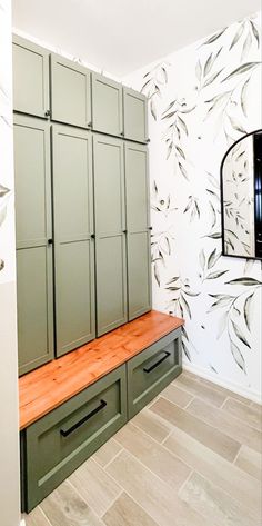 an empty room with green cabinets and wooden bench in front of wallpapered walls