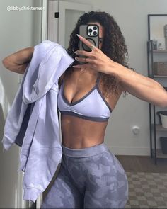 a woman taking a selfie with her cell phone while wearing sports bra and leggings