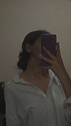 a woman taking a selfie with her cell phone in front of her face and wearing a white shirt