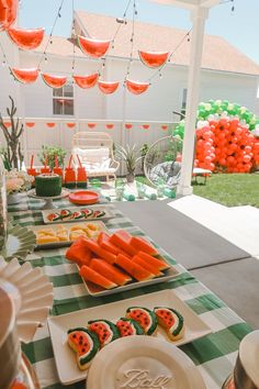 the table is set up for a party with oranges and watermelon decorations