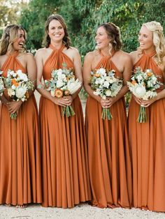 bridesmaids in orange dresses laughing and holding their bouquets at the same time