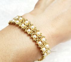 a close up of a person's arm wearing a bracelet with pearls on it