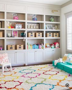 a living room filled with lots of white bookshelves next to a blue couch