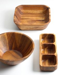 three wooden bowls, one with compartments and the other with dividers in them on a white surface