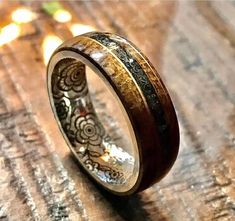 a wedding ring with an intricate design on it's side, sitting on a wooden surface