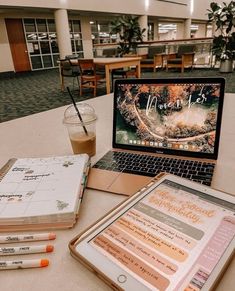 an open laptop computer sitting on top of a table next to a notebook and pencils