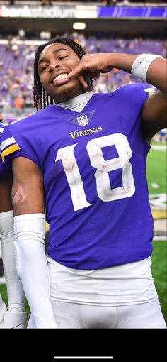 a football player with dreadlocks standing on the sidelines in front of an empty stadium