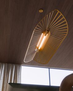 a light fixture hanging from the ceiling in a room with wood paneling and curtains