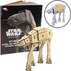 a wooden model of a star wars at - at is next to a copy of the book